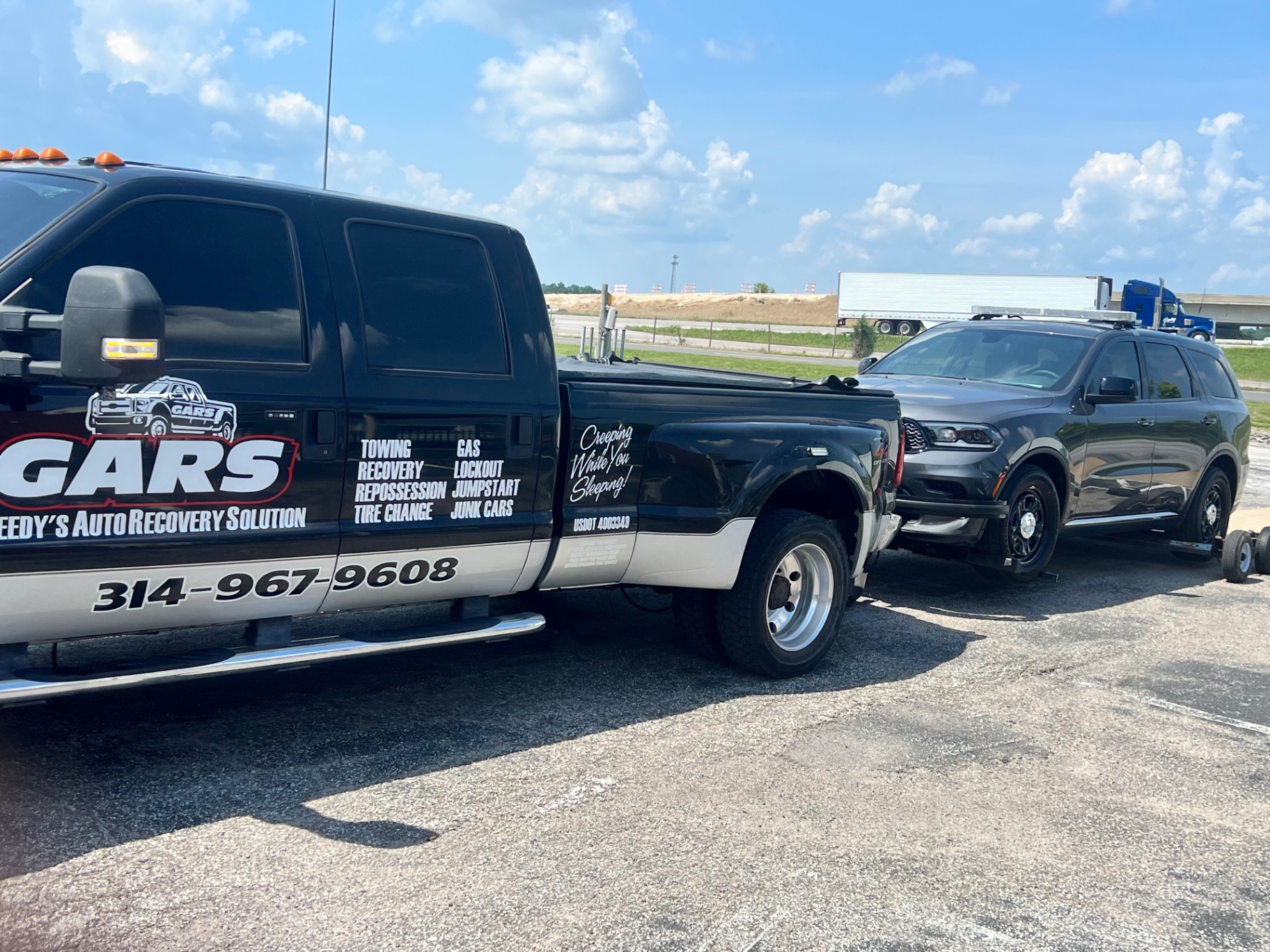GARS tow truck towing a Dodge Durango on the highway shoulder