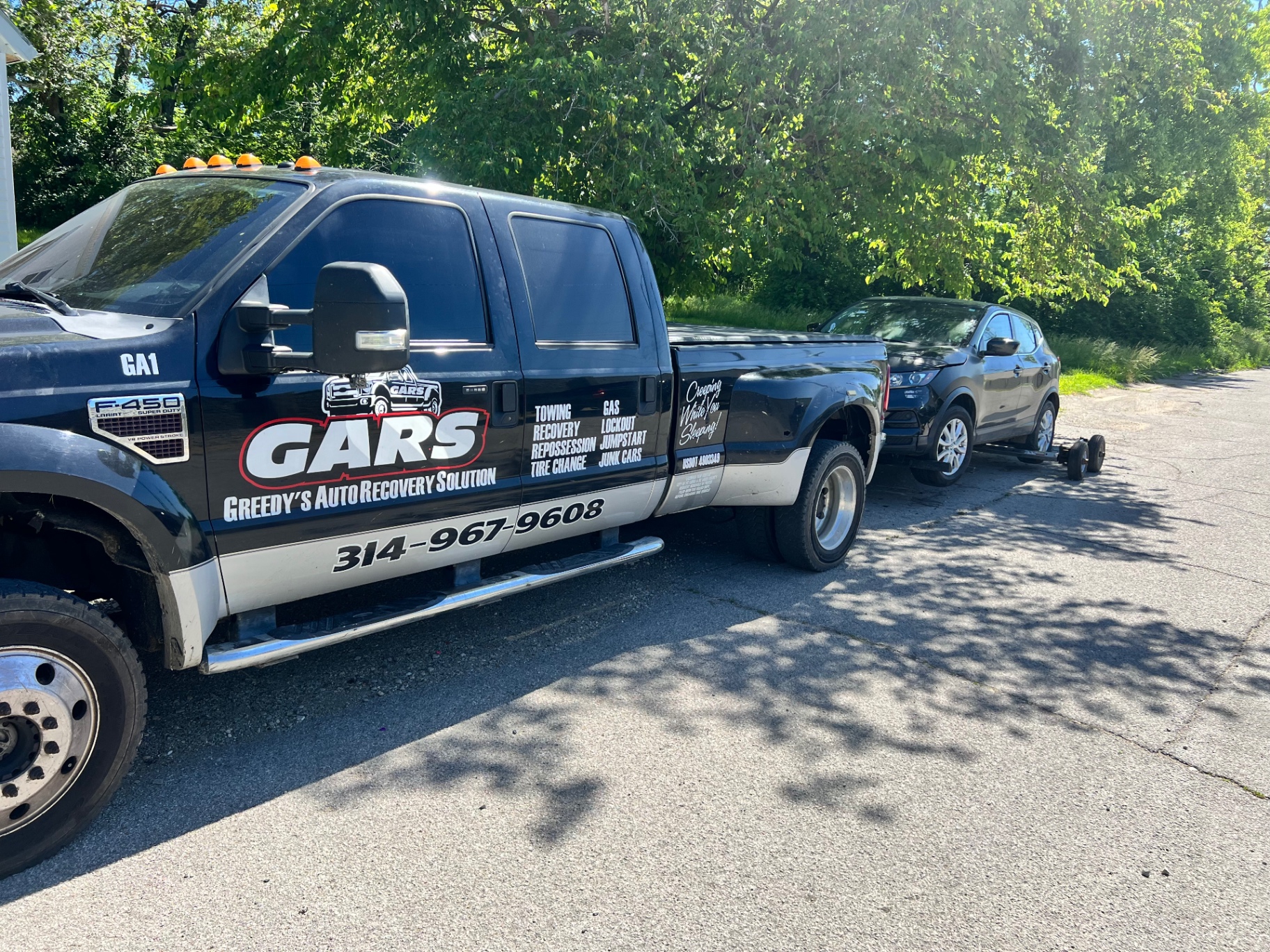 GARS tow truck towing a crossover on a tree-lined street